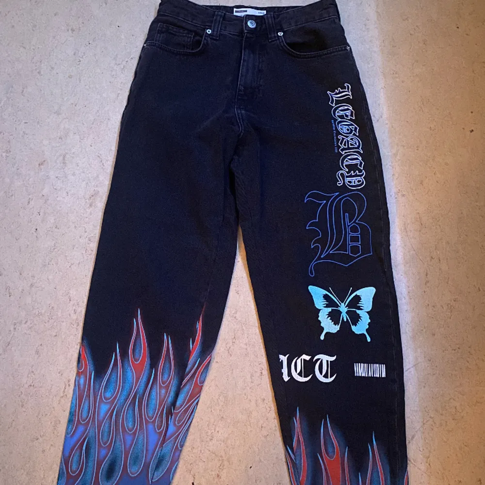 Svarta jeans med blå eldflammor och Y2K print, funkar för både tjejer och killar, Väldigt bra skick bara använd 1 gång(()). Jeans & Byxor.