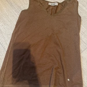 En fin glitter linne! - Detta är en fin glitter linne i en brons guldig färg. Det är väldigt festlig och passar till många event.