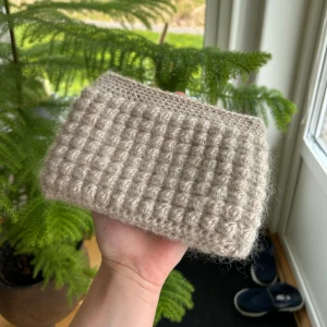 Necessär - Virkad necessär gjord av mig<3 Beige garn med beige och blått innertyg. Önskas fler bilder eller har du några frågor, är bara att skicka!💕 Gjord av  mohair och bomullsgarn, ca 11 hög och 16cm bred.