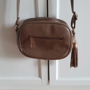 Handväska - Liten, brun handväska med tofs och dragkedja. Liten dragkedja inuti också. 