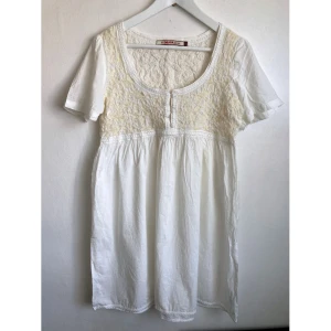 Vit kortärmad miniklänning, XL 48/50, bohemisk, boho, student, broderad, broderi, romantisk, sommar - Vit miniklänning i luftig bomull, klädda knappar fram, texturerad överdel, broderier. Mått i cm: bröstvidd 46; axelbredd 37; längd fram från axeln 83; ärmlängd 21,5.