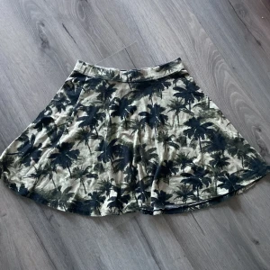 Mini kjol - Mini kjol från Gina med Palm mönster. Den är i strl xs men stretchig i midjan. Använd fåtal gånger och inga defekter finns.