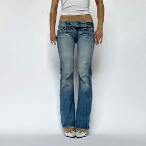 Lågmidjage vintage jeans med knappspänne i midjan. Modellen är 175 cm och bär 7 cm klackar & jeansen är lite för små för henne i midjan. Innerbenslängd: 80 cm Midjemått: 78 cm