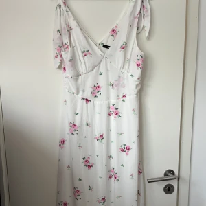 Blommig klänning  - Vadlång sommar klänning med v-ringning. Använd 1 gång Perfekt till midsommar/sommaren. Storlek M. Köparen står för frakten. Säljer för 200kr ny pris 599kr
