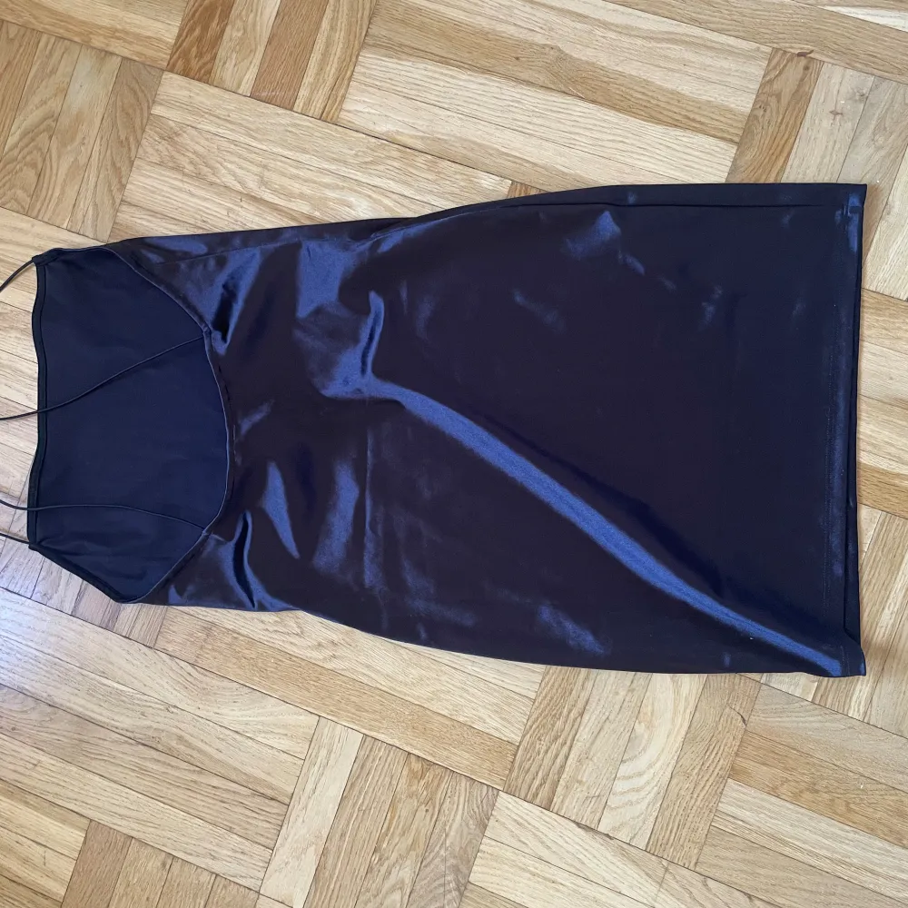 Kort klänning i svart glasigt tyg med smala axelband från H&M, stl M. Klänningar.