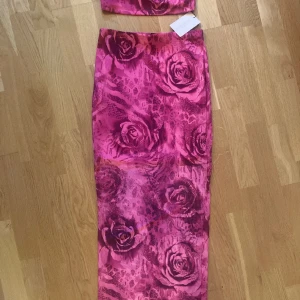 Fint set co-ord med rosor kjol och bandeau topp - Fint set! Aldrig använt. Storlek M. Undertyg på kjol.