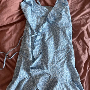 Omlottklänning - Blå omlottklänning med ett vit somrigt mönster! 