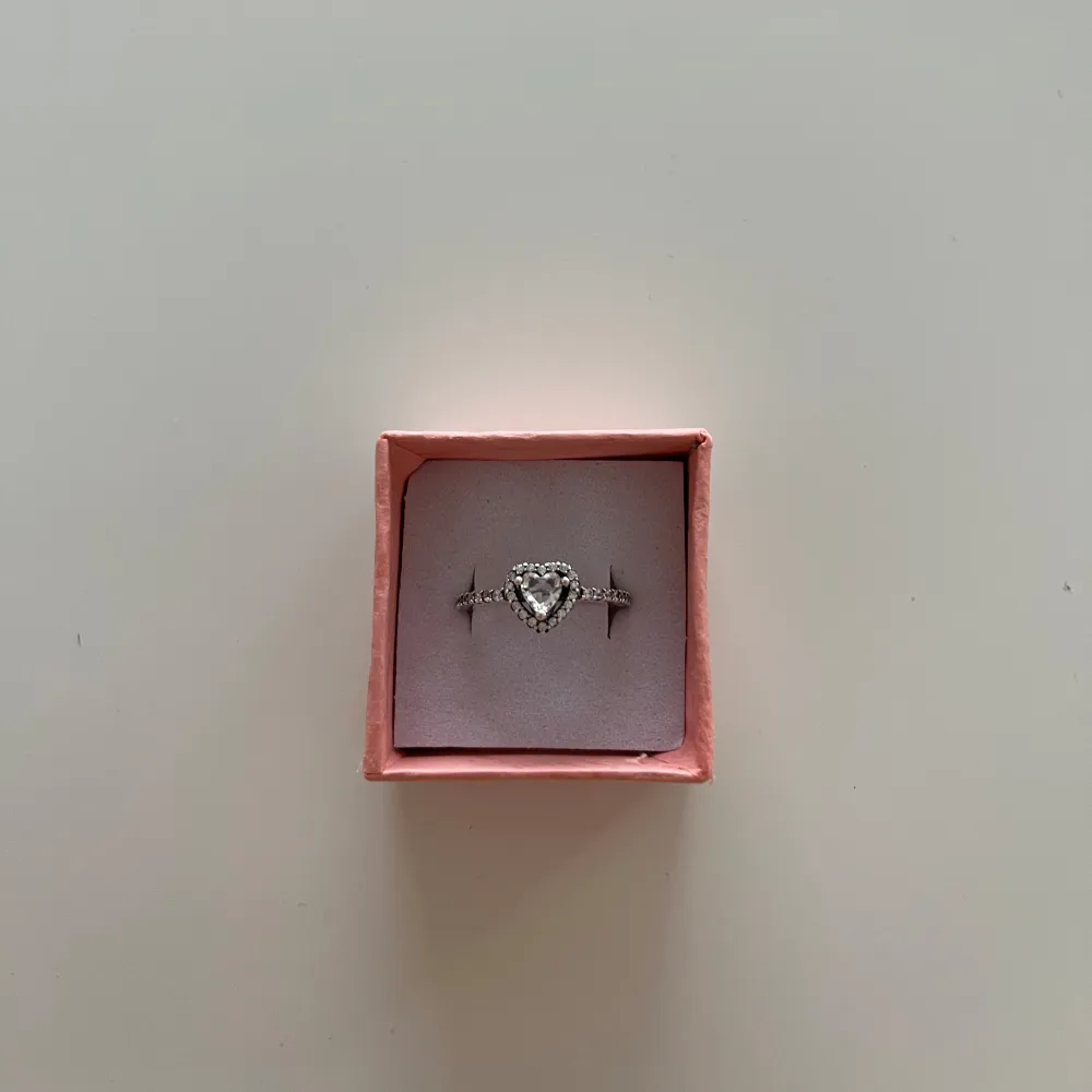 Silvrig ring från Pandora med silvrigt hjärta. Köpt av en annan tjej men den är tyvärr för liten för mina fingrar (storlek 6 enligt henne). Den lilla boxen ingår inte. Accessoarer.