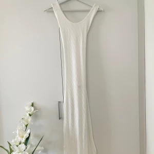 Stretchig Maxiklänning - Cremevit maxiklänning från Chiquelle med öppen rygg och slits på båda sidor.