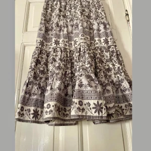 Så fin bohemisk maxikjol med resår i midjan - Otroligt vacker kjol i bomull med bred resår i midjan. Stl M men passar 36-42 enl mig. Vackert mönster i grå toner. Sparsamt använd i fint skick! Från Indiska 