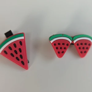 Vattenmelonformade hårklämma  - Ett par hårklämmör formade som vattenmelonskivor. hårklämmör är röda med gröna och vita detaljer samt svarta prickar som föreställer kärnor.2st
