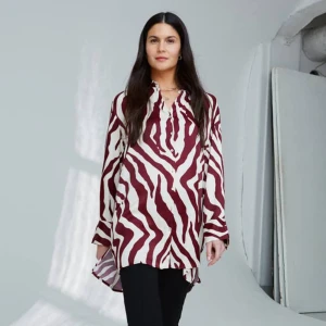 Snygg lång skjorta i sidenkänsla  - Härligt material med tyngd, i sidenkänsla av  100% luftig viskos. Märkt XS men rymlig/lös passform. Skulle säga stl 36-40, beroende på hur man vill att den ska sitta. Slutsåld snabbt i butik, ord pris 699:- creme/vinröd