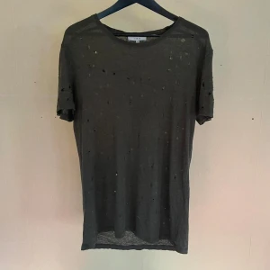 IRO- T-shirt ”distressed” I linne  - En grön (grå?) t-shirt från franska märket IRO i storlek M (Herr). Unisex präglad.  T-shirten är av 100% linne och har ett slitet ”distressed” utseende med små hål men trots är den utan tvekan i ett fint skick. linen. Unisex. -Material: 100% linen -