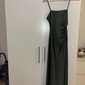 Zara klänning, Storlek S - Grön klänning med tunna axelband och en figursydd passform. Perfekt för en festlig tillställning eller en kväll ute.  Aldrig använd och prislapp kvar.  Material: 100% polyester. (Men imiterar sidenmaterial) 