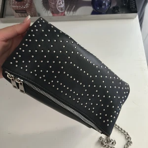 Väska  - Säljer en liten svart väska med silvriga ditaljer. Använd som skolväska men är i bra skick.