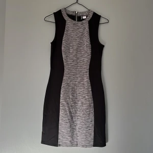 Klänning  - Grå, svart klänning med mindre dragkedja baktill. Klänningen är i storlek 38