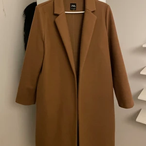 Kappa zara - Ljusbrun kappa från Sara i storlek L.  Fickor på sidorna somna i sidosömmen.