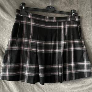 Next kjol i storlek 10 (EUR 38). Svart med grå och rosa Rut mönster. Köpte för ett par år sen men den kommer inte till användning då den inte passar mig/min stil längre. Kontackta gärna för frågor.