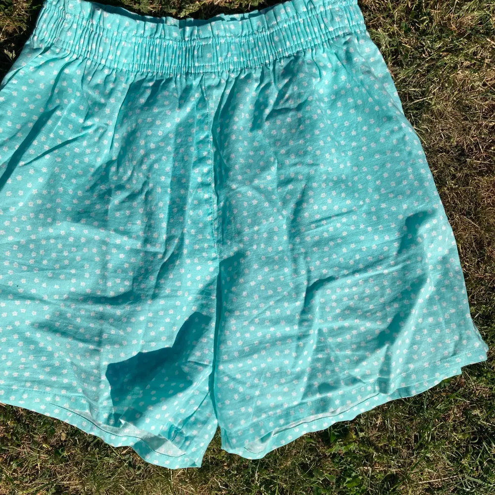 Ett par turkosa shorts med små vita blommor på. De är från H&M i storlek 164. Kontakta om du är intresserad!🥰. Shorts.
