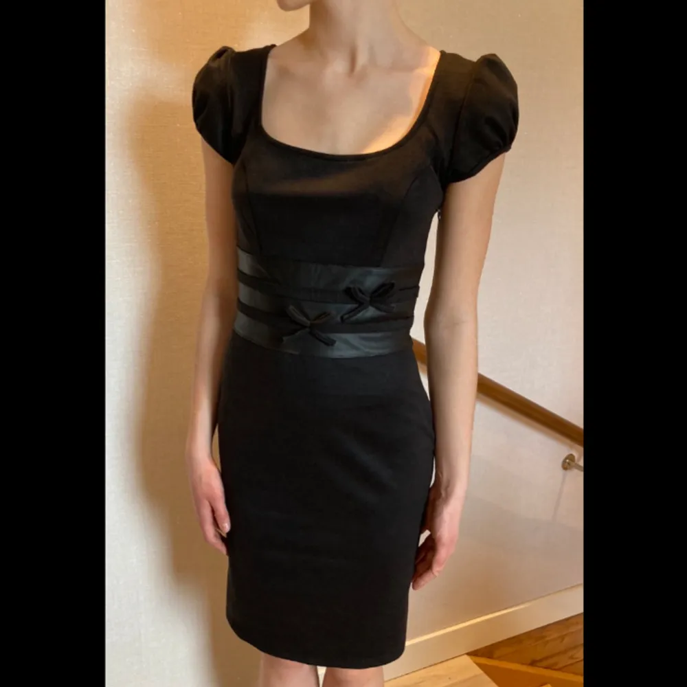  Super snygg svart klänning med läder sträck runt midjan och rvå små rosetter på framsidan🫶🏼 köpte i Barcelona på en elegant klänning butik för 1999kr och säljer nu för 400 eller bud⭐️ Säljer pg av att jag enbart behövde ha den 1 gång så den är som ny!. Klänningar.