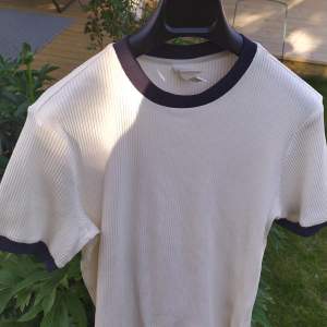 Oanvänd creme ribbad t-shirt i bomull med mörkt blå kanter, väldigt stretchig🤗