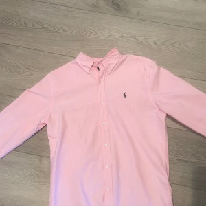 Ralph Lauren Skjorta  - Säljer denna rosa och stilrena skjorta ifrån Ralph Lauren eftersom den inte passar. Skicket är vänligt bra då den inte har kommit till så mycket användning. Storleken är M