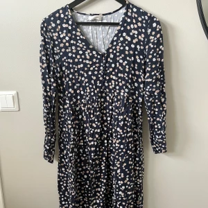 Klänning MSCH - Långärmad mörkblå blommig klänning från MSCH. Knappar fram vid urringningen