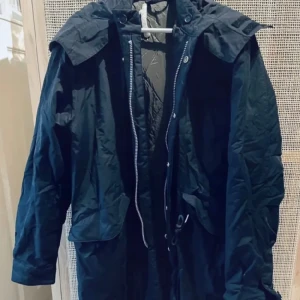 Whyred vinterparkas - Nypris 2300kr. Whyred Vincent Winter parka med huva, stl 48 I midnattsblå färg. Fodrad höst och vinterparkas. Oanvänd med skyddspapper kring jackans detaljer, se bilder. 