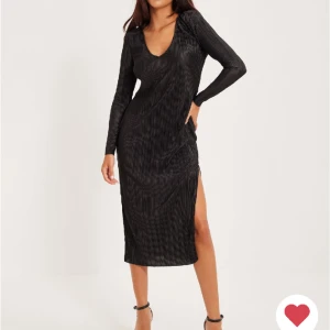 Långklänning med slits  - Lång svart klänning med slits och vadderade axlar.  Plisserat material.  Endast använd vid ett tillfälle, som i nyskick. 