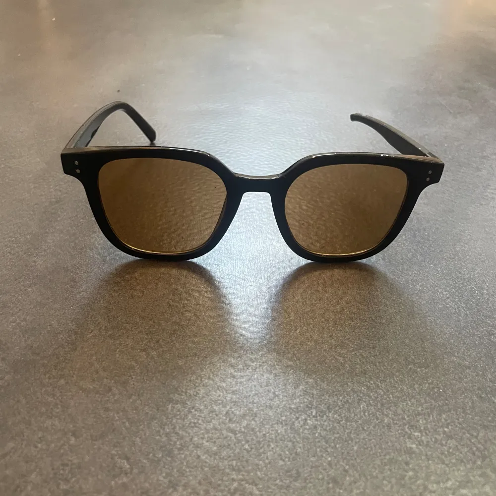 Solglasögon med svart båge och brunt glas. Ena tippen har gått av men det täcks av örat när dom sitter på. Riktigt snygga glasögon om man kan leva med att dom är olika långa.. Accessoarer.