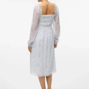 Sommarklänning  - Mellanlång vit sommarklänning med blå blommor. Köpt på Vero Moda. Storlek S.  Använd 3 gånger. Jätte söt klänning till sommaren, har själv köpt likadan i annan storlek😊🌸