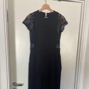 Byxdress från Zara - Byxdress från Zara.  Toppdelen har spets längst sidorna och nederdelen är som kostymbyxor med fickor.  Stängs i ryggen med dragkedja samt två knappar, varav en knapp saknas (enkelt att sy på). 
