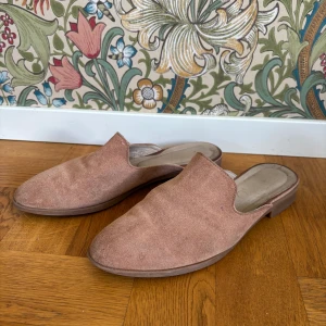 Mules slip ins i mocka/skinn storlek 38 - Märke Rylko. Bra kvalitet och material.. Mockaskinn och lädersula. Skorna är i använt skick. Se bilder! Sulan inuti skon sitter löst i främre delen (går att limma fast så den sitter på plats igen) 