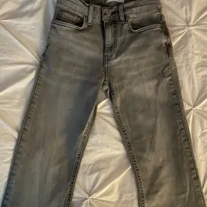 Lågmidjade utsvängda jeans i ljusgrå från Gina Tricot. Har några tecken på användning (lite trådar som sticker ut). Storlek 32