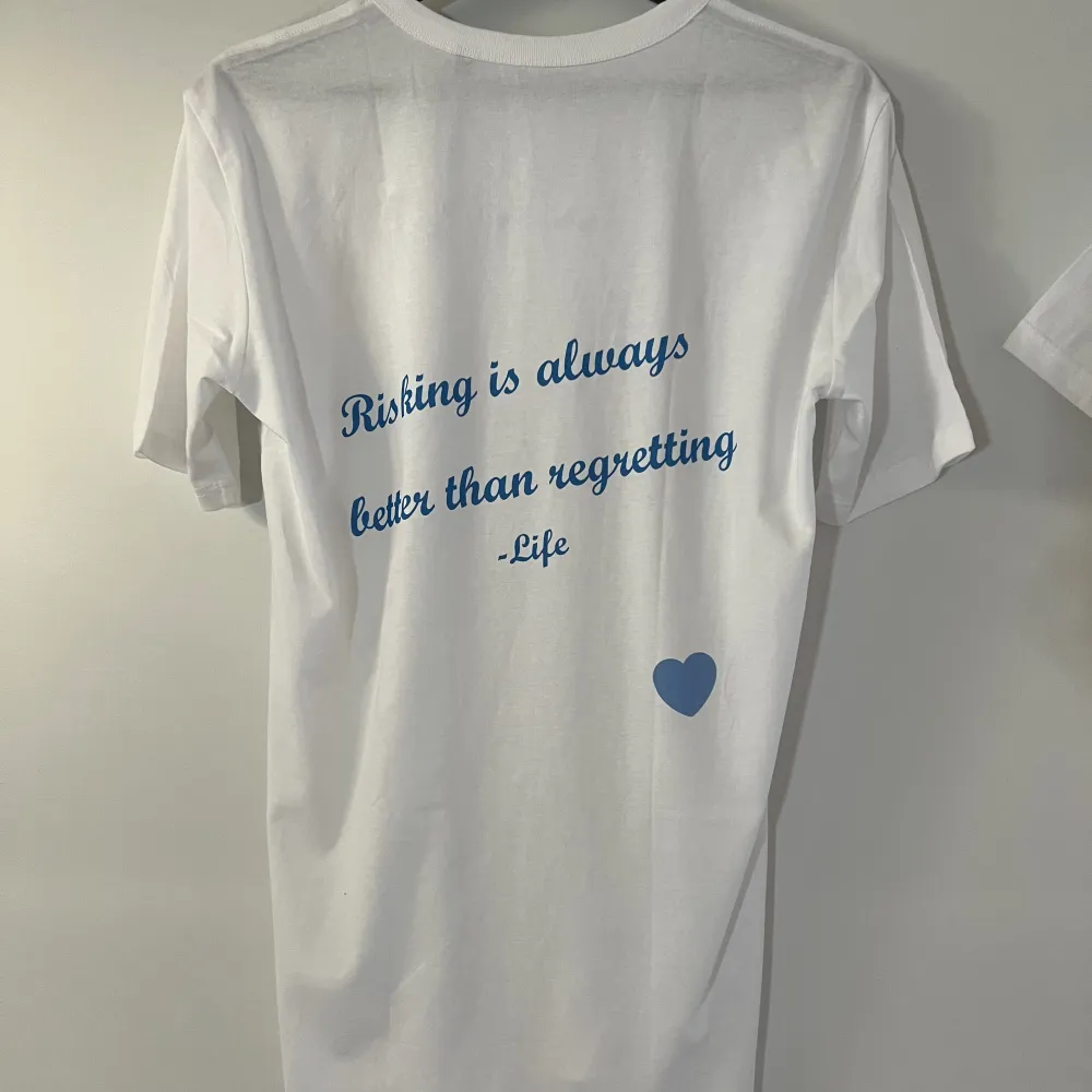 ”Risking Is always better than regretting” Vit t-shirt med blått tryck på ryggen. Storlek M. T-shirts.