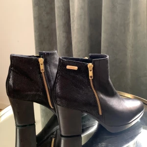 Dasia Stövletter snygga till hösten - Fantastiskt snygga stövletter från Dasia. Svarta med guld detaljer och liten platå framtill i äkta skinn. Har använts Max 2ggr därav säljer jag dem. Nyskick!