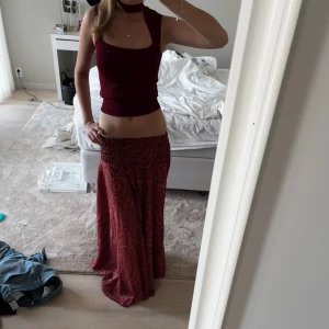 Röd långkjol - En röd långkjol som igentligen är byxor. Byxorna är så lösa att det inte syns utan det ser ut som en kjol. Köpt på Mallorca. Går till marken på mig som är 175 cm