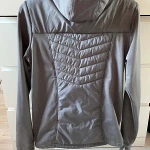 Grå funktionsjacka - Säljer en grå funktionsjacka som passar bra för träning, utevistelse eller rörelse. Väldigt fint skick, knappt använd. Storlek S herrmodell. 150kr