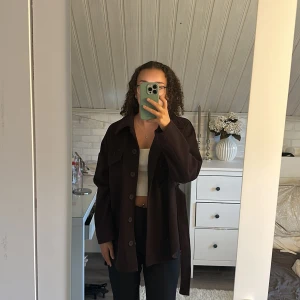 Mörkbrun kappa - Oanvänd mörkbrun kappa från Gina tricot i storlek xs