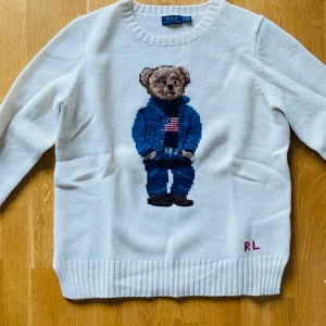 Polo Ralph Lauren tröja med nallebjörn  - Vit stickad tröja från Polo Ralph Lauren  med nallebjörn på framsidan. Använd endast en gång så i mycket fint skick. 