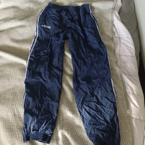 Blå adidas byxor - Coola byxor från adidas med super cool lös passform! Utsidan är i bra skick men inre lagret tyg har spruckit i sömarna på båda menen men inget som syns från utsidan💙