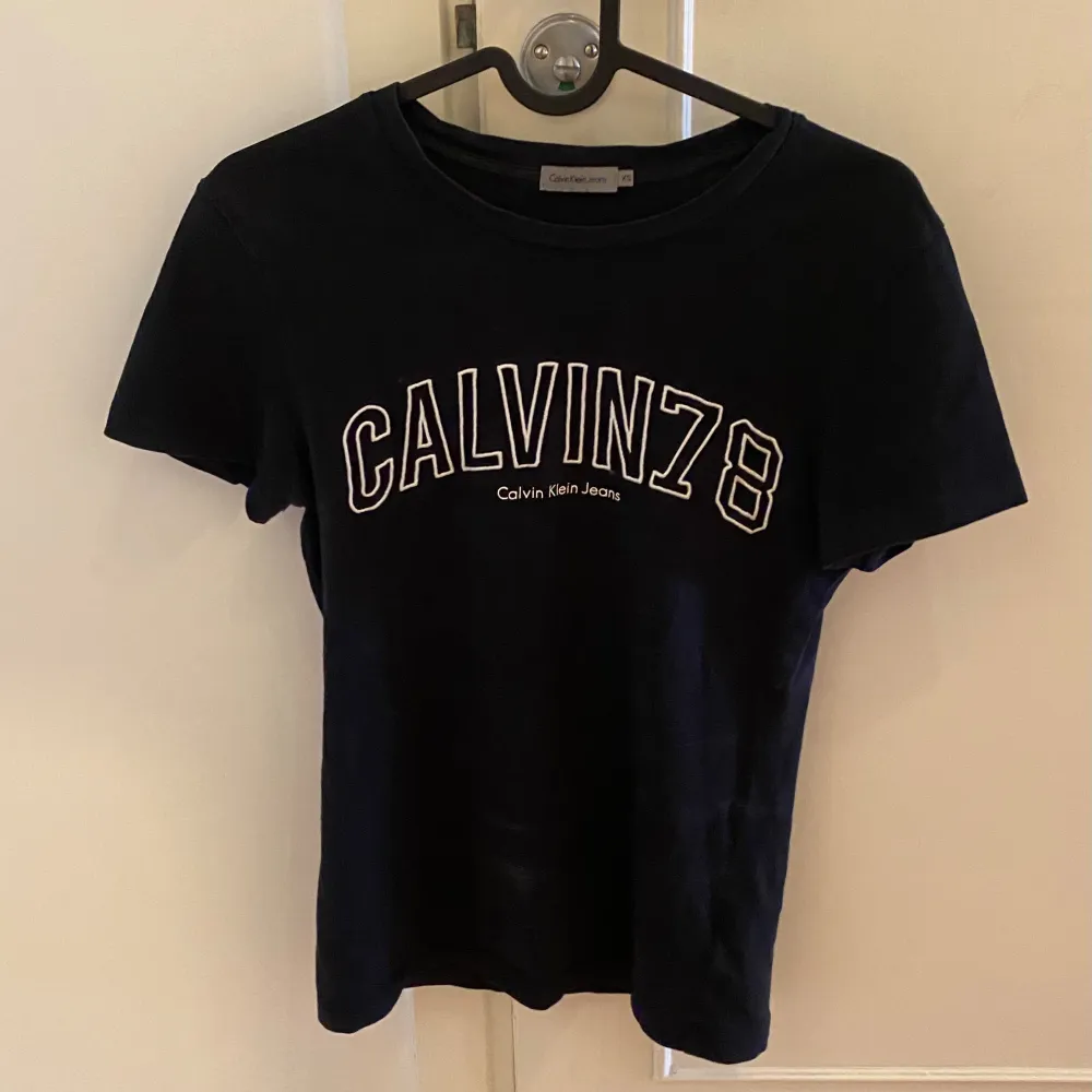 Svart T-shirt från Calvin Klein med vitt märke på bröstet som knappt kommit till användning. T-shirts.