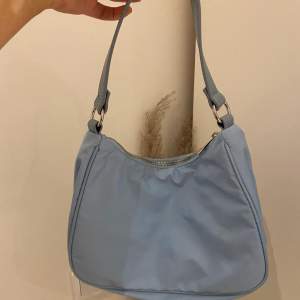 En blå handväska med två mindre fak på en av sidorna i väskan. Varan är från NELLY assessorer och har använts väldigt fåtal gånger. Den är i mycket bra skick! 