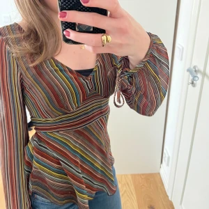 Boho ”70-tals” blus!! H&M med knytband och volang  - Fin och somrig Boho-blus från H&M. Nyskick. 🤎Tunnt material, brun med färgglada ränder. Volang nederst och knytband! Jättefin passform, inga fel. Pris kan diskuteras 🫶🏼