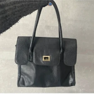 Vintage väska - -50%. Fint skick på denna vintage väska som passar till allt. Rymlig men ändå lätt att få med sig och bära! Är lite osäker på färgen, men bilden stämmer mot verkligheten!