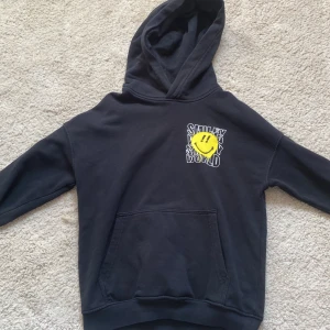 Svart hoodie med en smile på  - Svart hoodie med en smile på i storlek 134/140