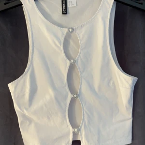 Vit topp - Vit topp från hm. Aldrig använd. Fina strassdetaljer fram. Kolla gärna mina övriga annonser :)