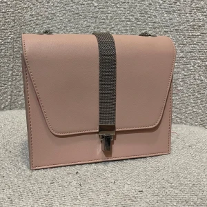 Axelremsväska  - Ljusrosa väska med silvrig kedja och lås. Använt ca 3 gånger. Insidan är mörkrosa med ett litet fack som stängs med dragkedja. Fungerat bra som finare festväska 💕 Skriv för fler bilder. Pris kan diskuteras ✉️