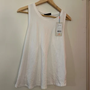 Vit linnetopp från Even&Odd Active - En vit linnetopp från Even&Odd Active. Toppen har en rund halsringning och är ärmlös. Baksidan har ett nätmönster och en öppen design som ger en luftig känsla.