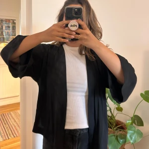 Svart kimono  - En tunn kimono som är kortare med superfint svall. Funkar perfekt över andra toppar.  Köpt second hand, bra skick.   